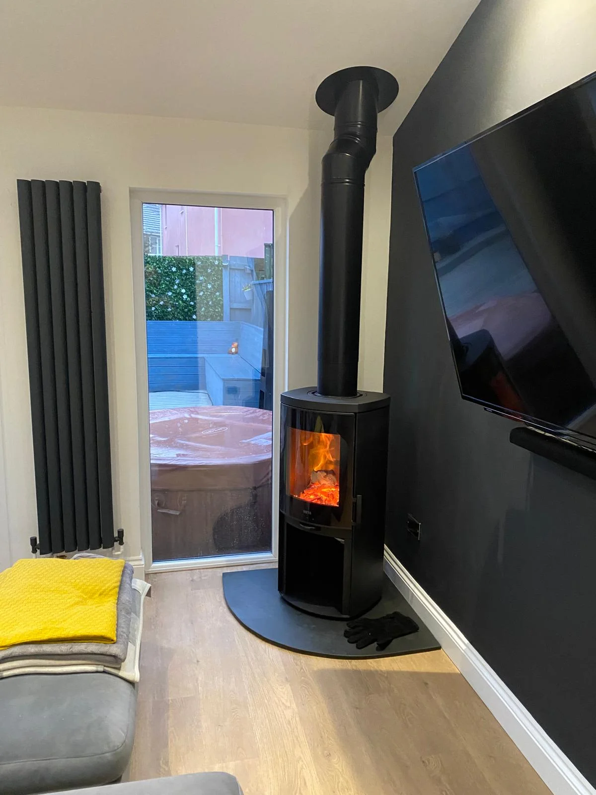 Black freestanding wood burning stove with tall flue pipe installed in modern living room Cornwall